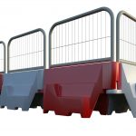 A series of interconnected pyramid-shaped barriers with panels, arranged in a row. The barriers have a sturdy base and are colored alternately in red and white. Each barrier is topped with a metal railing that connects them all together, creating a continuous line of demarcation or protection. The background is plain white, highlighting the colorful and geometric design of the barriers.